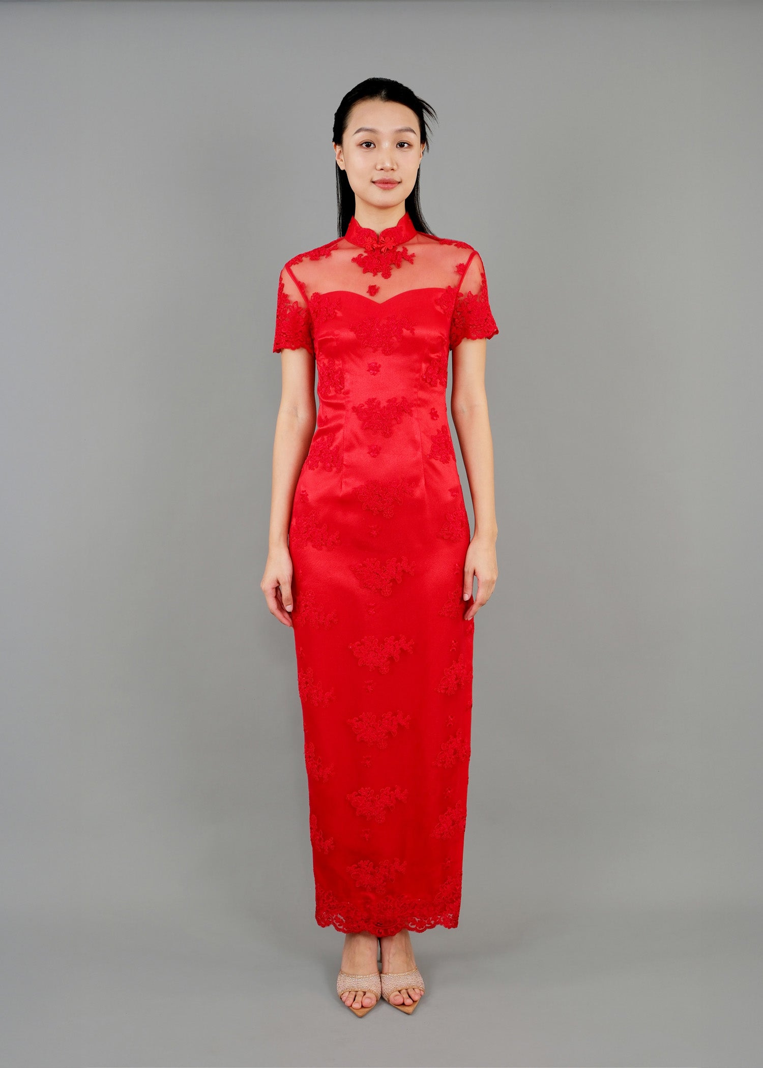 A woman stands in front view, wearing a red high-neck dress with sheer sleeves and floral lace details.
一名女子站在前面，身穿紅色高領連身裙，透明袖子上飾有花卉蕾絲。