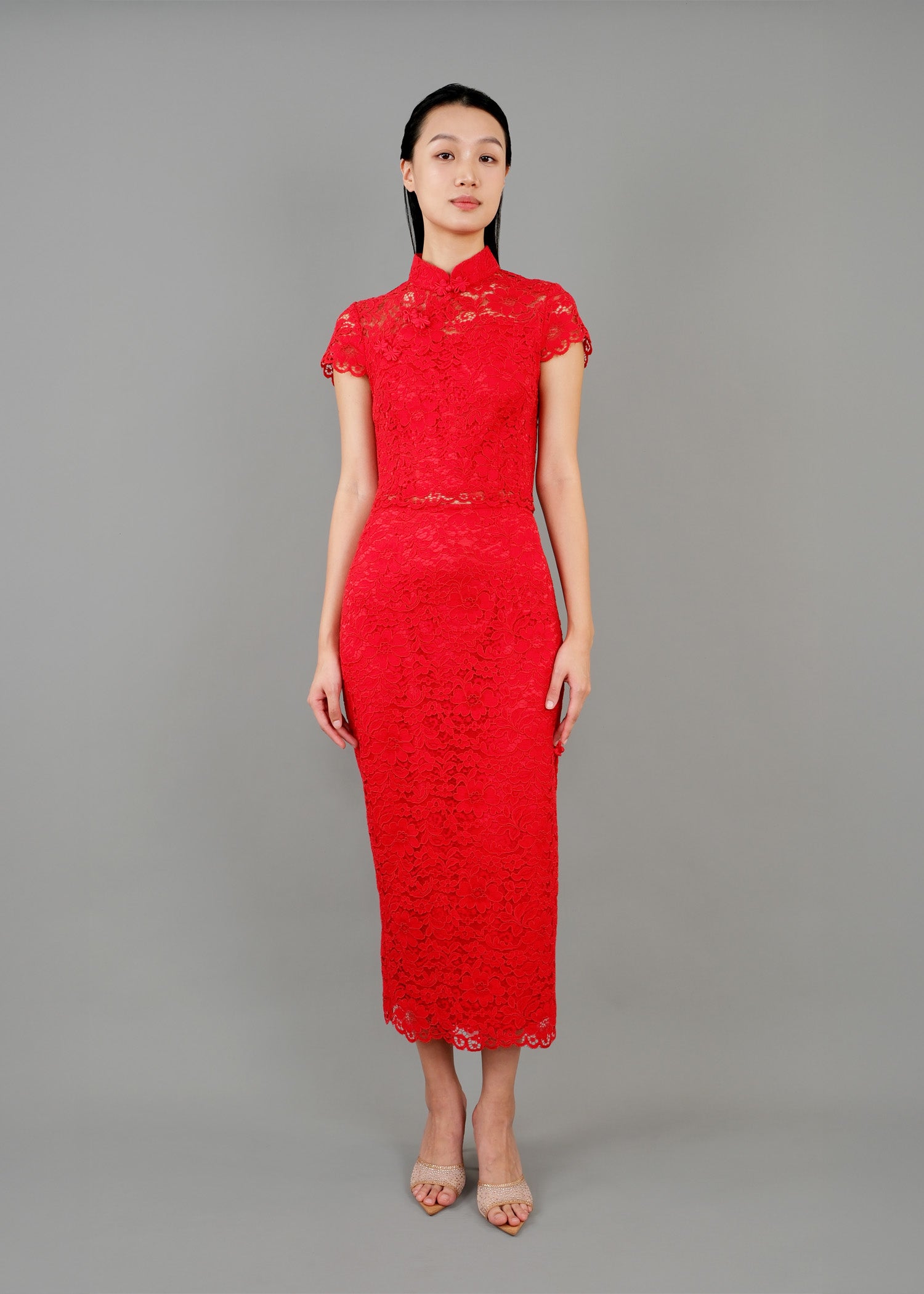 A woman stands in front view, wearing a red lace high-neck, short-sleeved dress that reaches mid-calf, featuring intricate lace detailing.
一名女子站在正面，身穿紅色蕾絲高領短袖連身裙，長及小腿中部，帶有精緻的蕾絲細節。