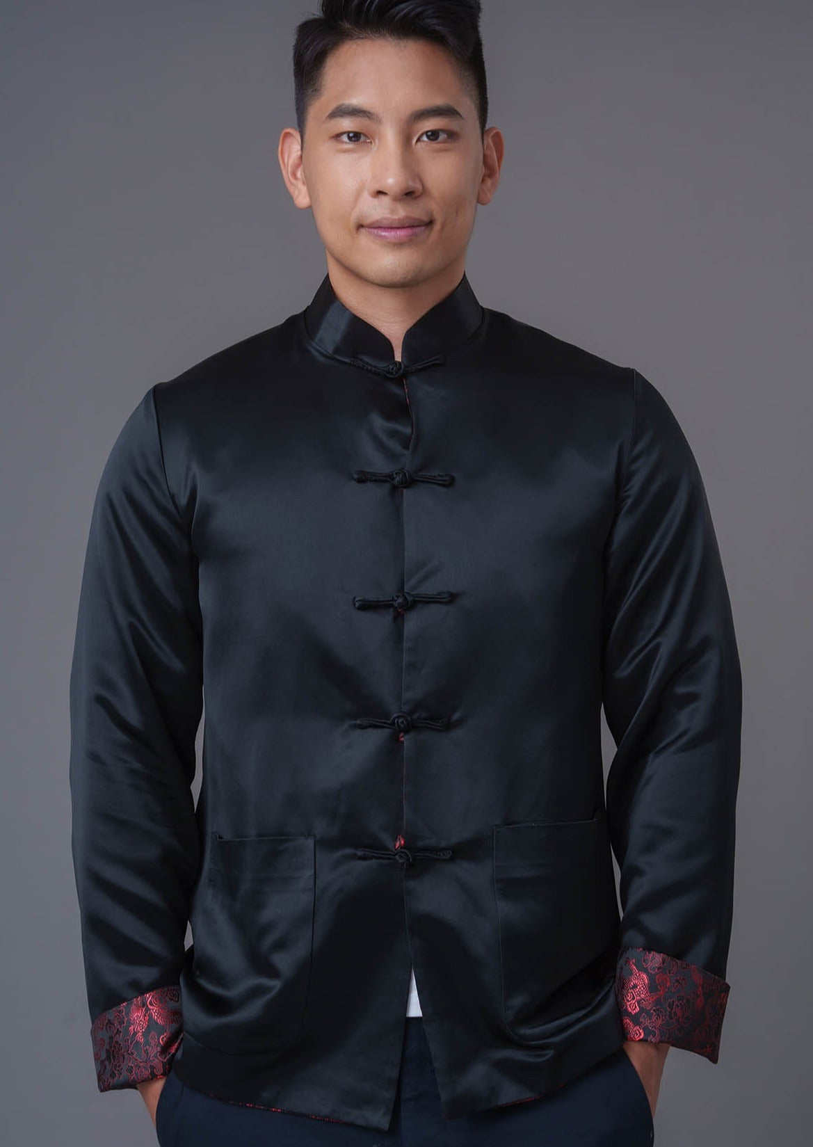 An asian Man wearing a black stain x red tiger brocade Tang Jacket against a gray background. 一位亞洲男子，以灰色為背景，穿著黑色緞面與紅色虎紋錦緞的唐裝外套。