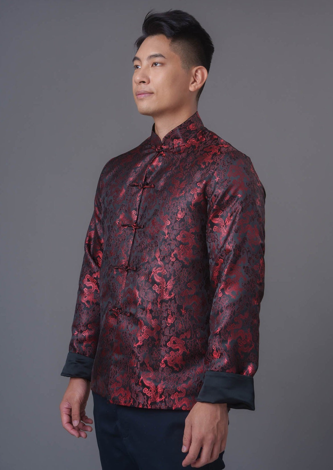 An asian Man wearing a black stain x red tiger brocade Tang Jacket against a gray background. 一位亞洲男子，以灰色為背景，穿著黑色緞面與紅色虎紋錦緞的唐裝外套。