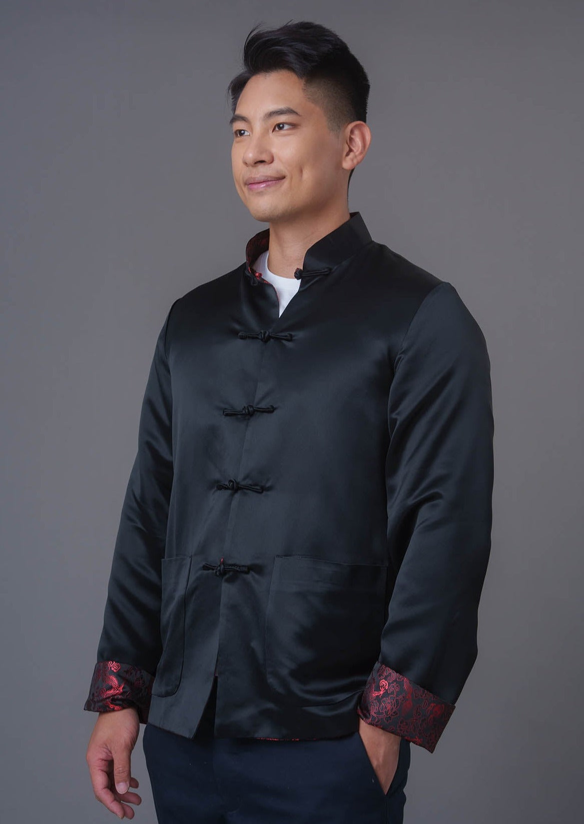 An asian Man wearing a black stain x red tiger brocade Tang Jacket against a gray background. 一位亞洲男子，以灰色為背景，穿著黑色緞面與紅色虎紋錦緞的唐裝外套。