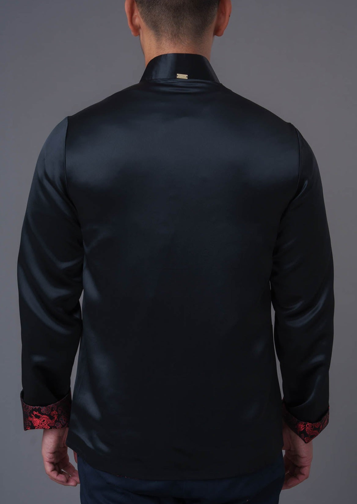 An asian Man wearing a black stain x red tiger brocade Tang Jacket against a gray background. 一位亞洲男子，以灰色為背景，穿著黑色緞面與紅色虎紋錦緞的唐裝外套。