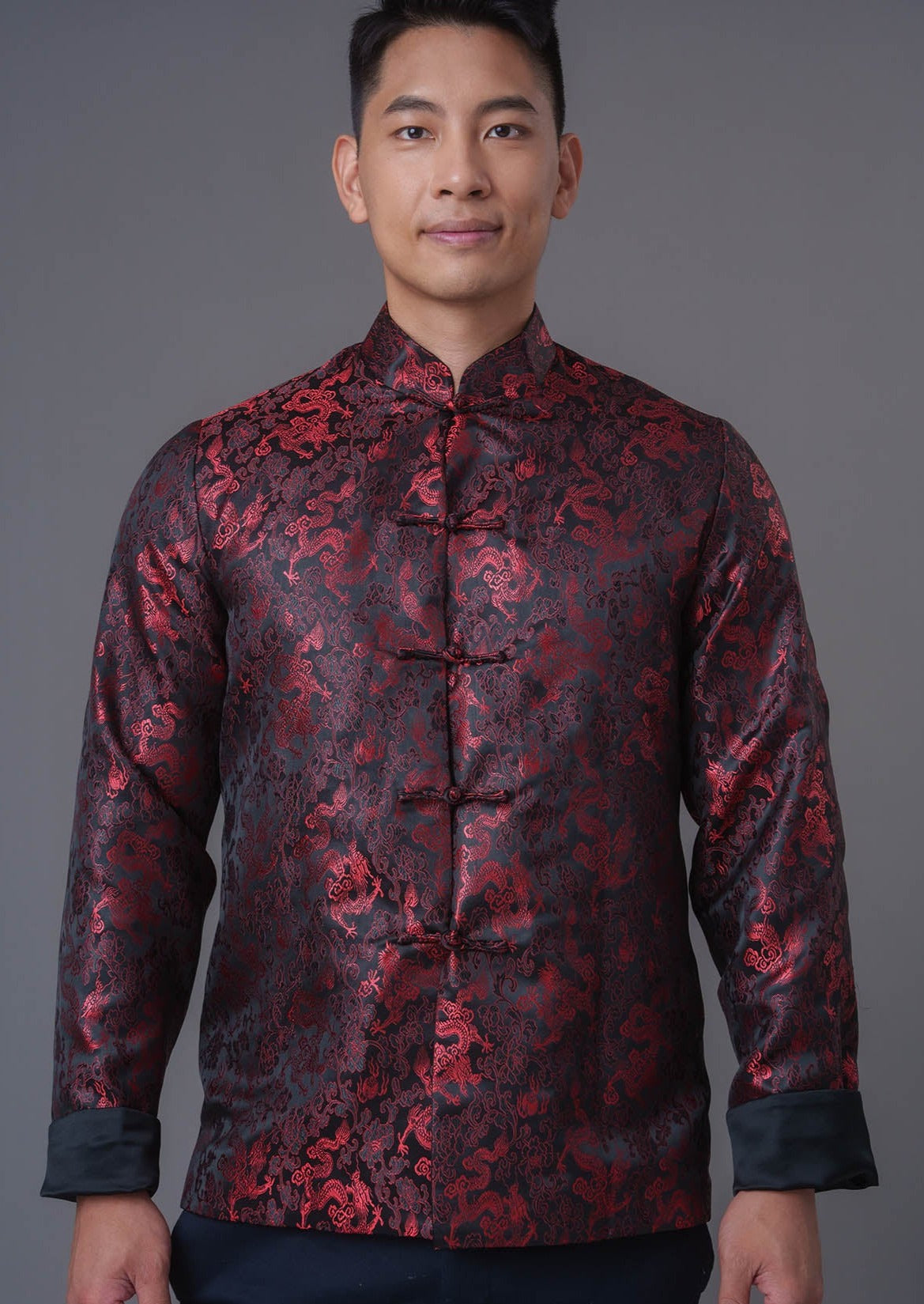 An asian Man wearing a black stain x red tiger brocade Tang Jacket against a gray background. 一位亞洲男子，以灰色為背景，穿著黑色緞面與紅色虎紋錦緞的唐裝外套。