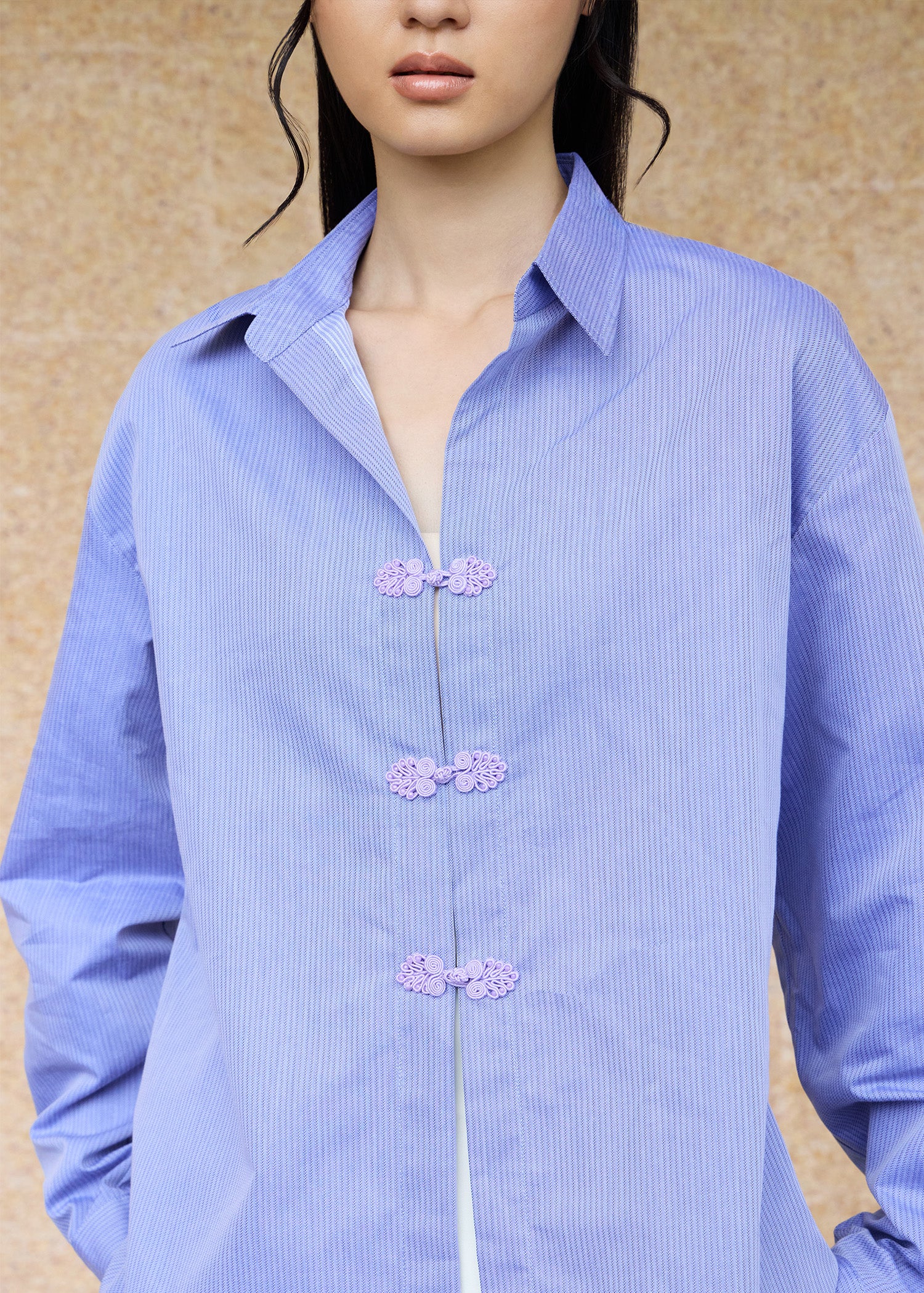 Close-up of an Asian woman wearing a periwinkle blue oversize shirt with pankou buttons