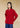 Front view, half-body shot of an Asian woman wearing a red knitted Tang jacket over top by Qipology, set against a yellow-beige background.