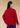 Back view, half-body shot of an Asian woman wearing a red knitted Tang jacket over top by Qipology, set against a yellow-beige background.