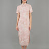 A woman stands in front view, wearing a light pink embroidered cheongsam dress. The dress features intricate floral patterns and a fitted silhouette with a high collar and short sleeves. 
一名女子站在正面，身穿淺粉色刺繡旗袍。旗袍飾有精緻的花卉圖案，修身剪裁，高領短袖。