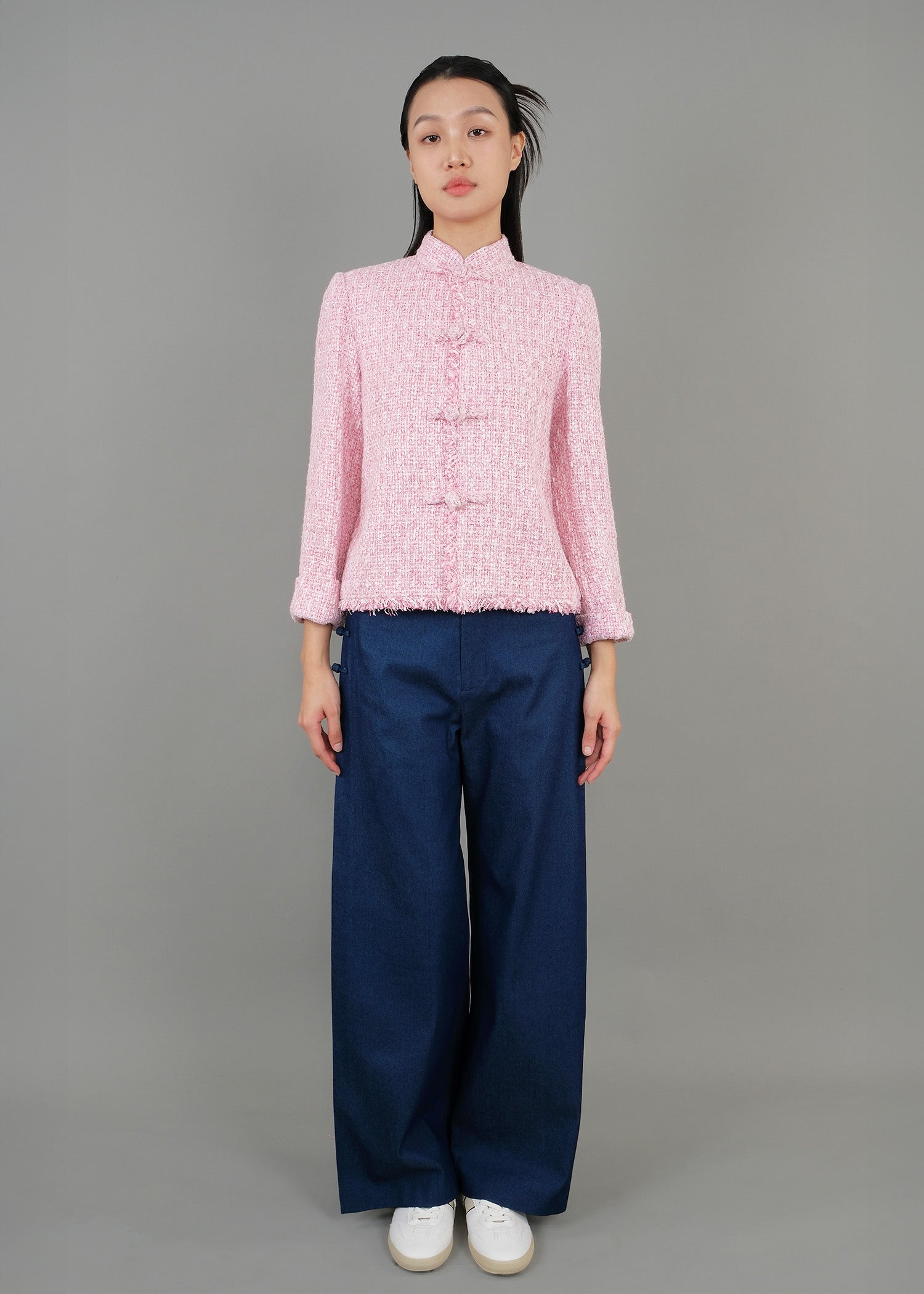 A woman stands in front, wearing a pink high-neck short-sleeved top paired with loose blue pants, showcasing a fashionable casual style.
一名女子站在正面，穿著粉紅色的高領短袖上衣，搭配寬鬆的藍色褲子，展現出時尚的休閒風格。