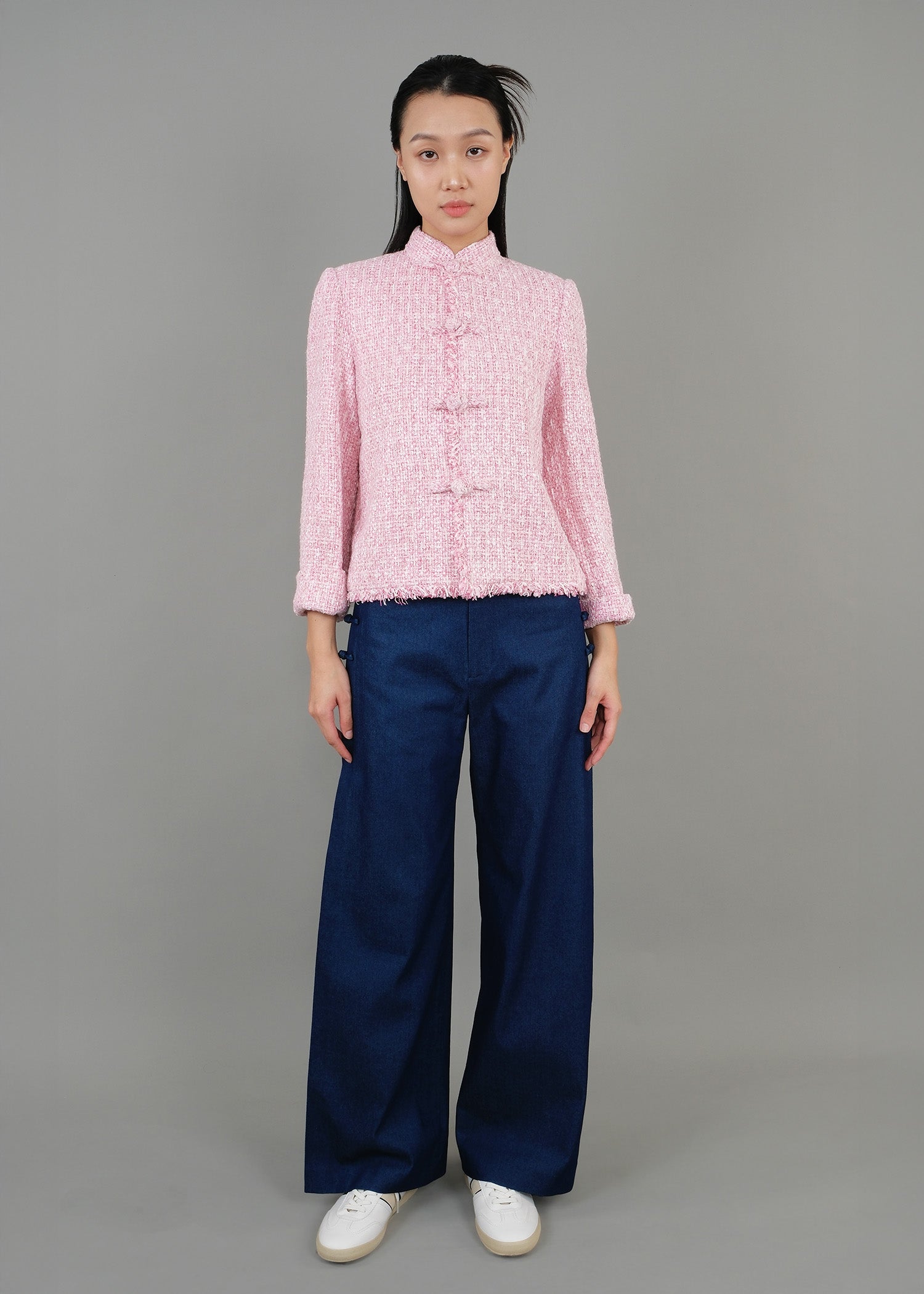 A woman stands in front, wearing a pink high-neck short-sleeved top paired with loose blue pants, showcasing a fashionable casual style.
一名女子站在正面，穿著粉紅色的高領短袖上衣，搭配寬鬆的藍色褲子，展現出時尚的休閒風格。