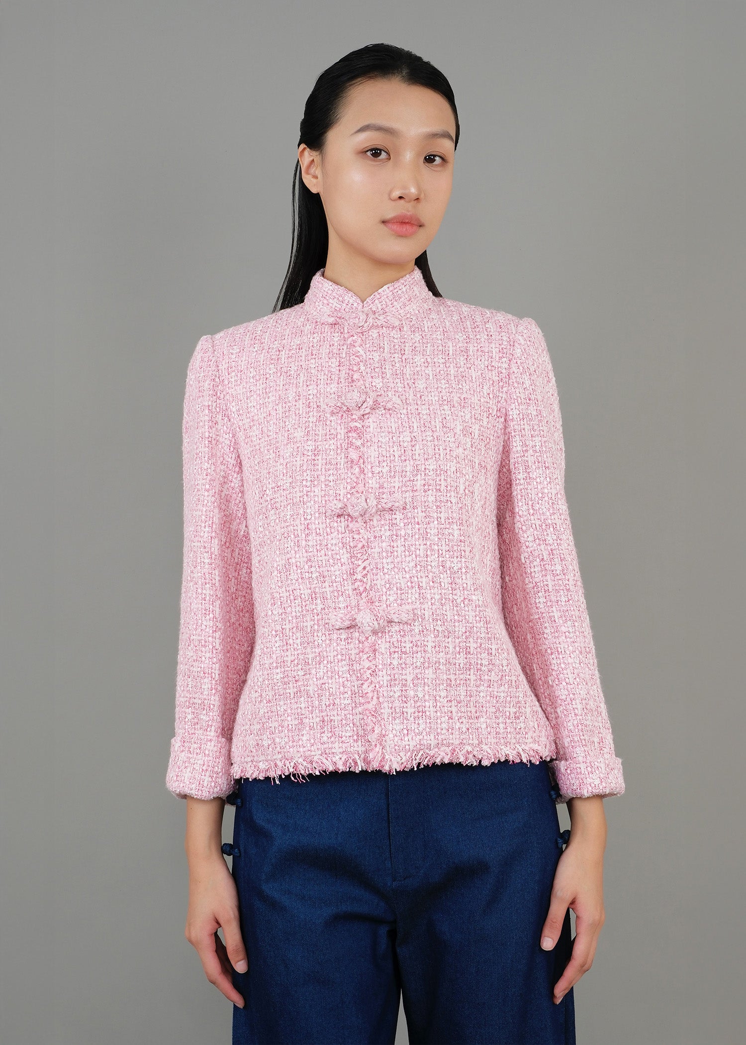 A woman stands in front, wearing a pink high-neck short-sleeved top paired with loose blue pants, showcasing a fashionable casual style.
一名女子站在正面，穿著粉紅色的高領短袖上衣，搭配寬鬆的藍色褲子，展現出時尚的休閒風格。