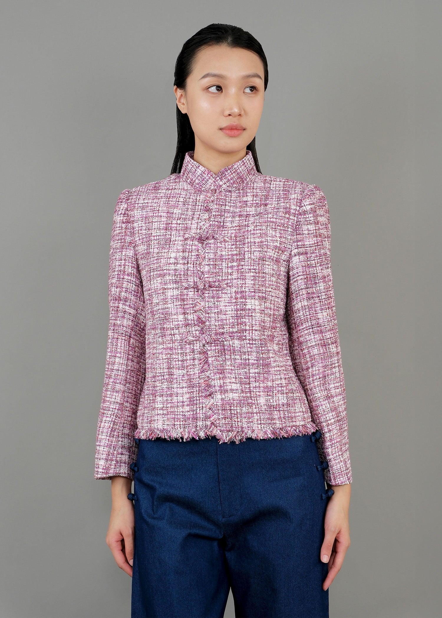 A woman stands in front view, wearing a pink textured jacket with a high collar and long sleeves, paired with wide-legged blue pants. She completes the outfit with white sneakers.
一名女子站在正面，身穿黑色亮片高領長袖外套和粉紅色紋理高領長袖外套，搭配藍色寬褲。她腳踩白色運動鞋，褲子開衩。