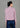 A woman stands in back view, wearing a pink textured jacket with a high collar and long sleeves, paired with wide-legged blue pants. She completes the outfit with white sneakers.
一名女子站在背影中，身穿黑色亮片高領長袖外套和粉紅色紋理高領長袖外套，搭配藍色寬褲。她腳踩白色運動鞋，褲子開衩。