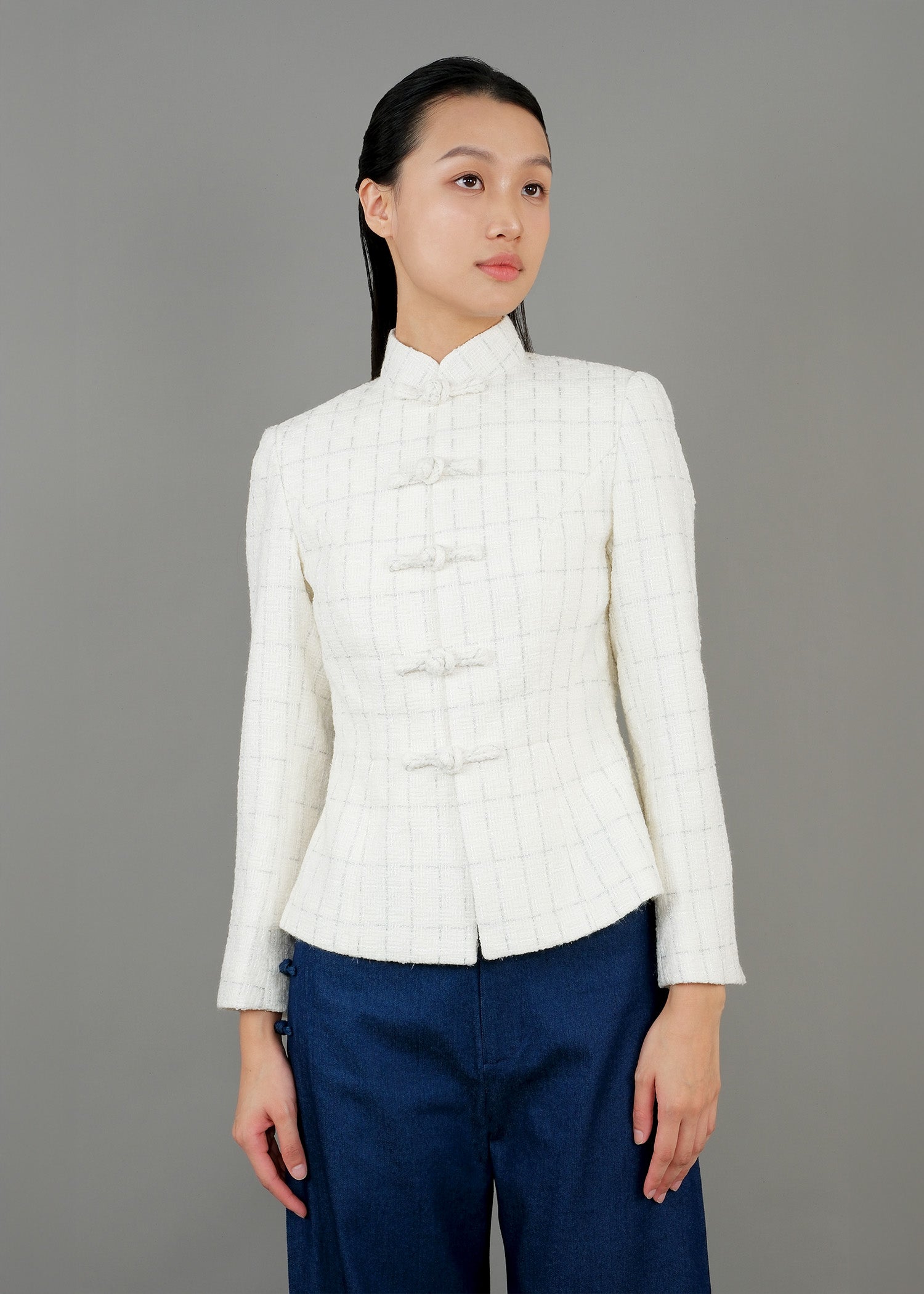 A woman stands in front, wearing a white high-collared jacket with button details and loose-fitting dark blue wide-leg trousers, paired with white sneakers, showcasing a modern and elegant style.
一名女子站在正面，身穿白色高領外套，具有連結細節，搭配寬鬆的深藍色寬褲和白色運動鞋，展現出摩登優雅的風格。
